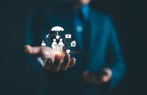 Business professional holding a holographic display of insurance protection symbols including family, umbrella, home, health, and financial icons, representing comprehensive life insurance coverage for self-employed individuals.